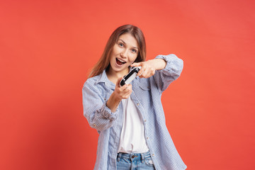 Excited casual young woman playing video games having fun on red background