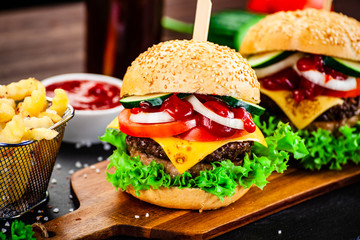 Tasty burgers with chips served on cutting board