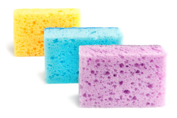 Colored sponges for washing dishes and other domestic needs. Yellow, blue and purple sponges are located one after the other at a slight angle. Isolate