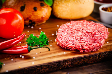 Fresh raw steaks on cutting board with vegetables