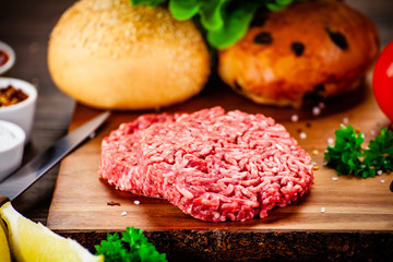 Fresh raw steaks on cutting board with vegetables