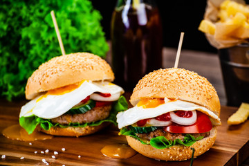 Tasty burgers with chips served on cutting board