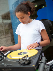 girl (12-14) mixing record on turntable