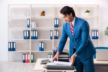 Young employee making copies at copying machine 