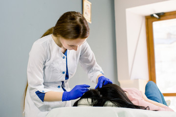 Procedure of mesotherapy. Young woman doctor cosmetologist making injections in woman's head for...