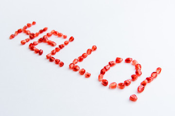 the word "hello" from pomegranate seeds on a white background