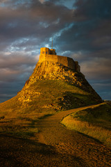 Obraz premium Dramatic Castle sunset near the Northumbria cost, England 