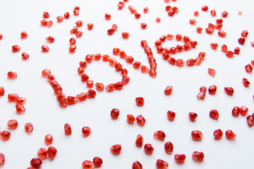the word "love" from pomegranate seeds on a white background