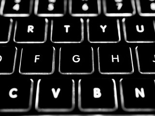 Black and white close-up on illuminated keys of computer keyboard.