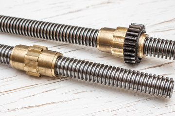 Trapezoid screw with bronze nut on white wooden background.
