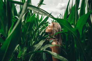 Young woman poses at corn field. Carefree woman enjoying freedom outdoors.