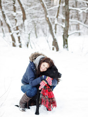 Fototapeta premium Beautiful young woman playing with her dog.Labrador retriever on a background of winter forest