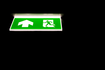 Green emergency exit sing in darkness