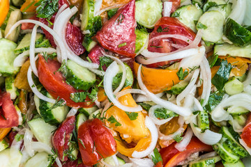 Fresh vegetable salad close-up background - tomatoes, onions, cucumbers, greens. Healthy eating.