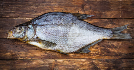 One dried salted fish bream on a wooden table, vintage style, top view