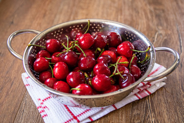 Fresh organic sweet cherries in a metal bowl for washing