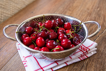 Fresh organic sweet cherries in a metal bowl for washing