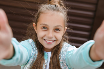 Portrait of a funny little girl taking a selfie in city