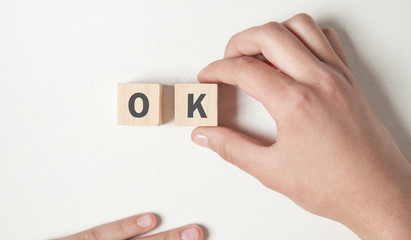 Hand showing wooden cube with a word OK.