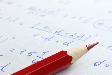 sharpened red pencil on the background of mathematical formulas in notebook close up. checking and solving problems