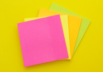 Colorful paper stickers on yellow background, blank note papers with copyspace.