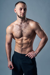 Muscular shirtless man standing with hands on hips