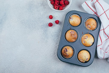 Baked Raspberry Muffins on a cooling rack on blue concrete table background. Top view, copy space. Breakfast concept