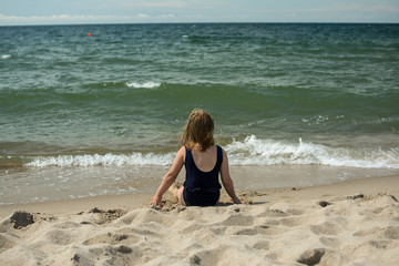 Fototapeta na wymiar little girl by the sea bright sunny day blue sky