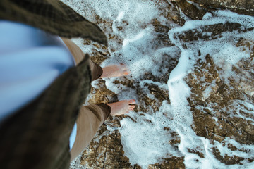 overhead view man barefoot walking by sea rocky beach