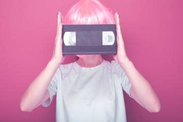 Young girl 90s and VHS cassette on pink background.