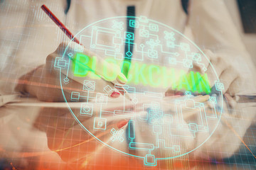 Cryptocurrency hologram over woman's hands writing background. Concept of blockchain. Double...