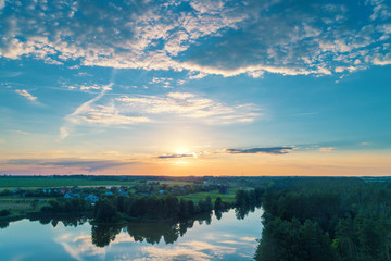 Magical sunset over the countryside. Lake with a beautiful reflection of the sky in the water. Rural landscape