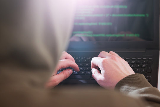Hackers programmer look on screen and writes the program code hack information and user account