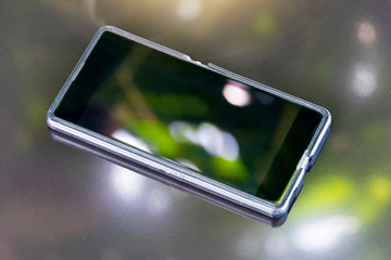 Blurred images of luxury mobile phones on a gray background With a reflection on the top glass.