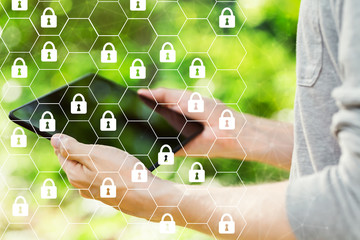 Cyber security theme with young man holding his tablet computer outside