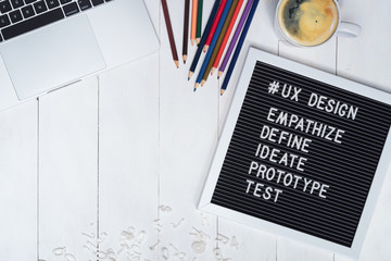 Creative flat lay photo of UX designer working desk and ux design process text on black felt board....