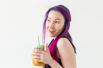 Portrait of a positive young mixed race and hipster girl with colored hair holding fruit protein smoothie on a white background. Healthy lifestyle concept