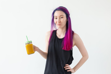 Cute young mixed race hipster girl with colored hair drinks fruit smoothie before starting a yoga class on a white background. Healthy lifestyle concept. Copyspase.