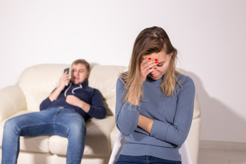 domestic violence, abuse and family concept - crying woman and her husband on the background