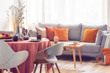 Stylish grey chairs at dining table covered with long tablecloth