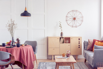 Vintage wooden coffee table and commode in elegant living room interior with grey couch