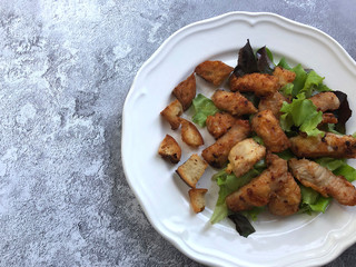 Gourmet Salad. Grilled chicken breast on lamb's lettuce garnish with delicately roasted white bread cubes on blue stone background.