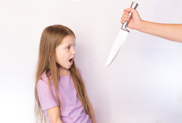 The little girl, frightened looks on the knife that it swung on a light background
