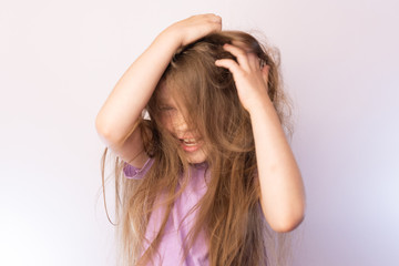 Fototapeta premium Little cute girl playing with long hair, fun, laughing, on a light background
