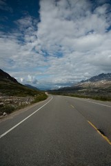 Wide angle view of road leading towards blue mountains in distance