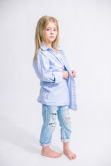 Beautiful fashionable little girl with blond hair in jeans clothes on a white background in studio