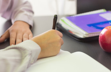 Fototapeta premium the student writes in a notebook, doing homework at his Desk