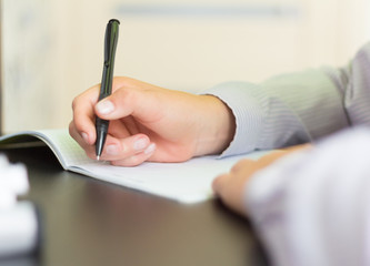 the student writes in a notebook, doing homework at his Desk