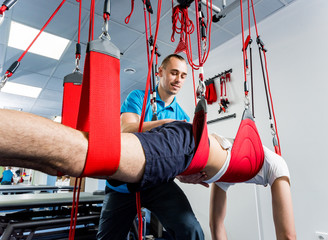 Physiotherapy. Suspension training therapy. Young man doing fitness traction therapy with...