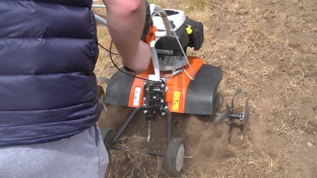 Strong man hands working with petrol cultivator on plowing townhouse yard